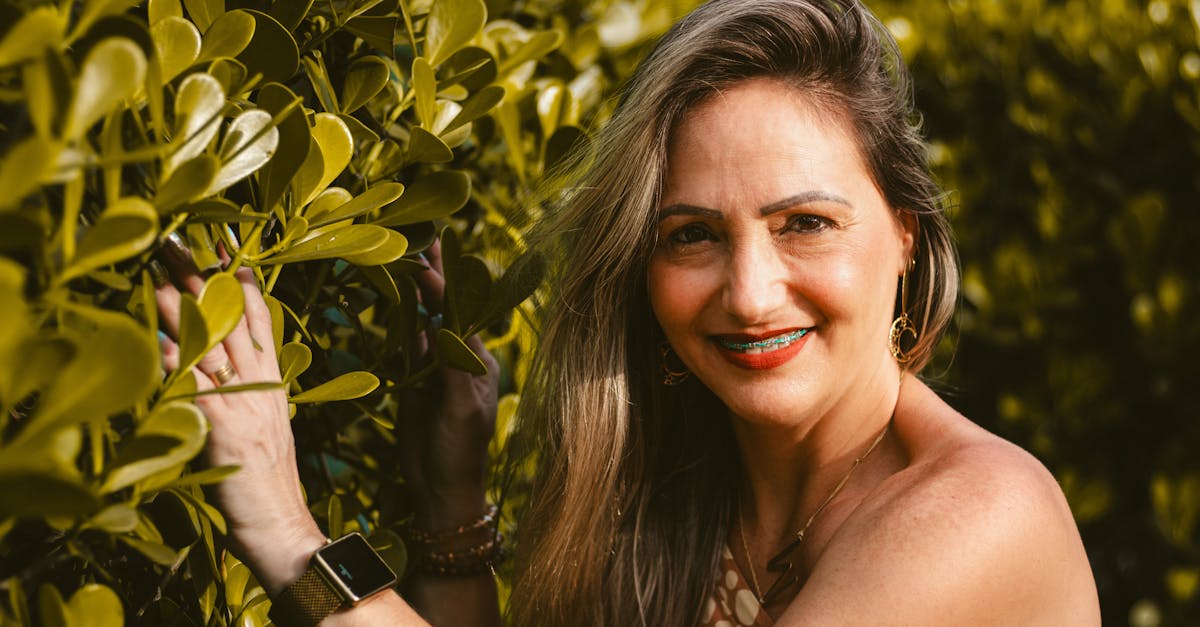 a woman in a tank top leaning against a bush